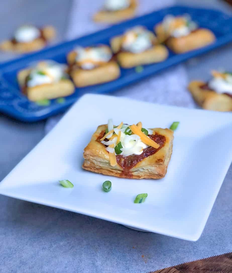 hormel chili on top of puff pastry square on a plate with sour cream