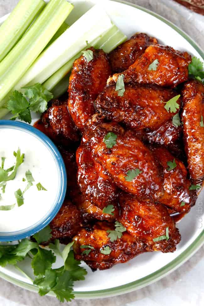chicken wings smothered in sauce with ranch on the side.