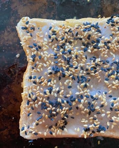 shrimp toast with sesame seeds on a baking sheet.