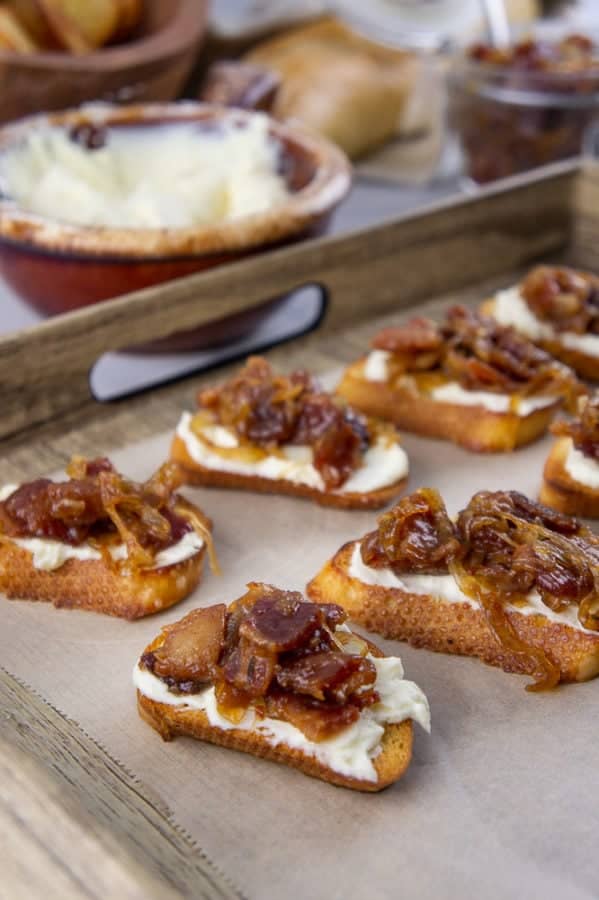 bacon jam crostini on a baking sheet with onions.