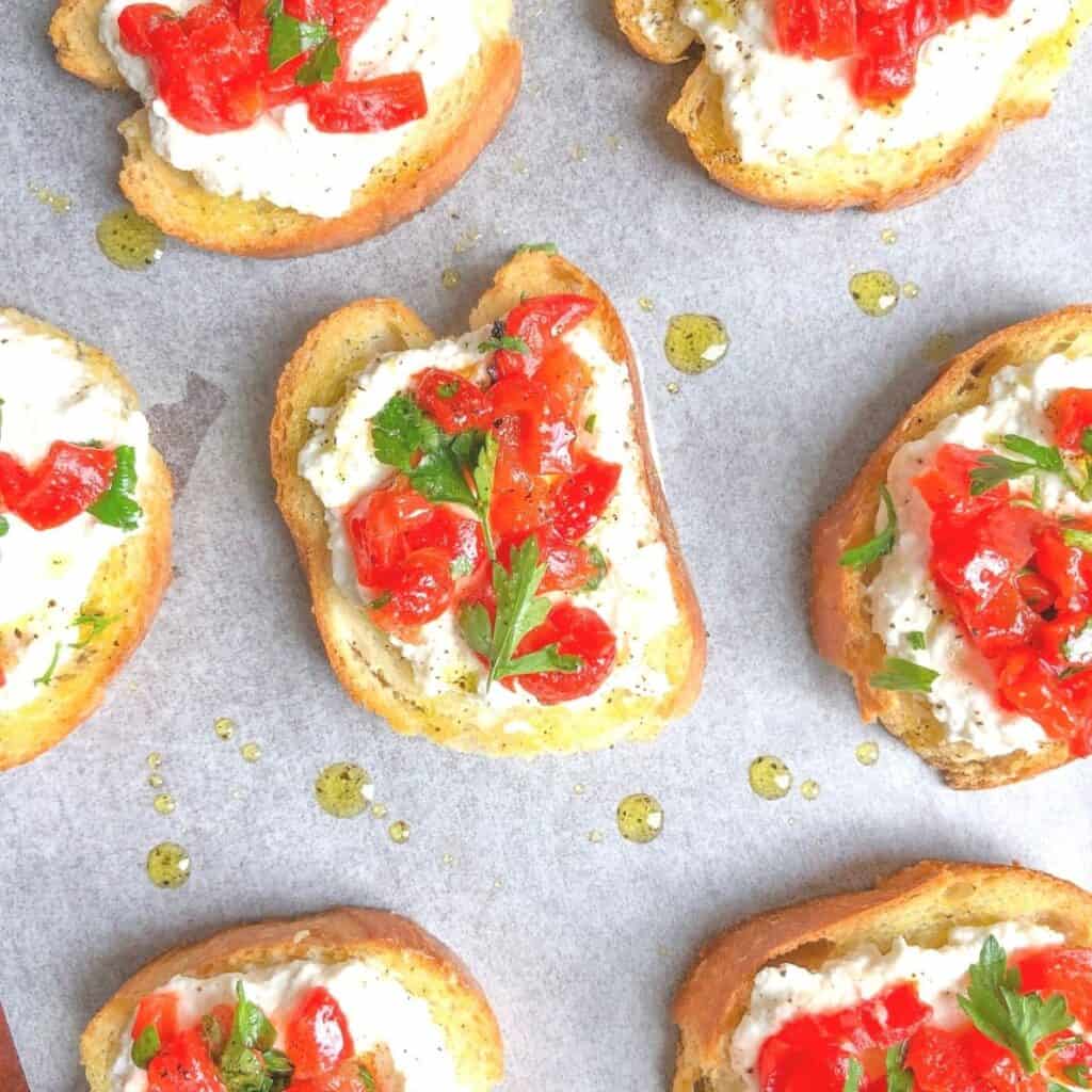 roasted red pepper crostini with ricotta cheese on parchment.