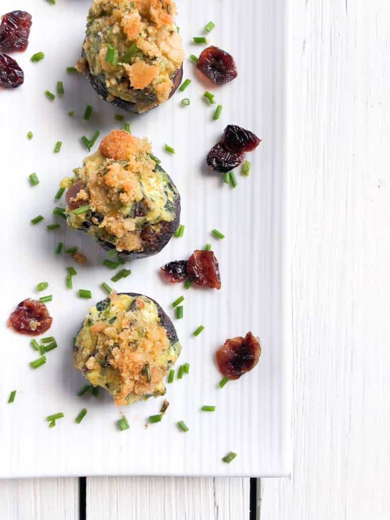 mushrooms appetizer stuffed with cheese topped with breadcrumbs and craisins on the side