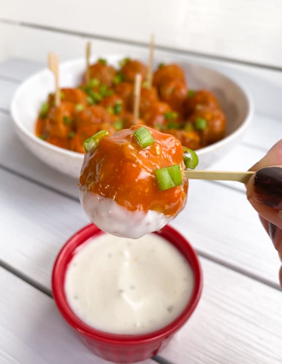 spicy and sweet buffalo chicken meatballs on a skewer dipped in blue cheese dressing.