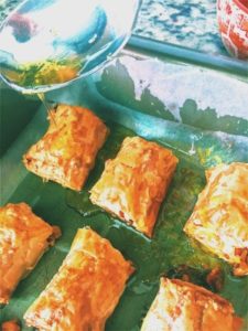 Mini baklava rolls pouring with honey.