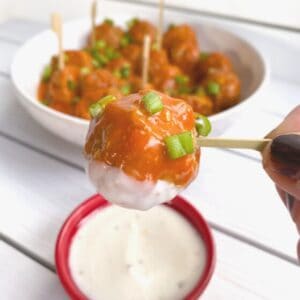 Crock Pot buffalo chicken meatball on a skewer with blue cheese sauce.