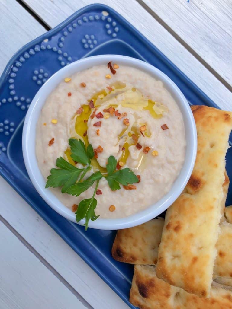 white bean dip on a blue plate with bread on the side