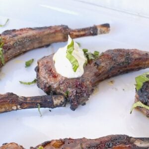 lamb chop lollipops on a plate with yogurt sauce.