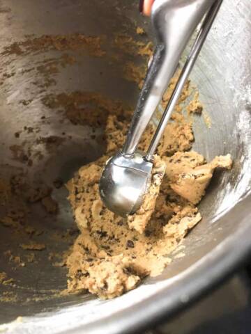 Scooping dough with chocolate chips from mixer.