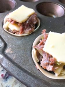 Steak mixture in a wonton cup with cheese on top.