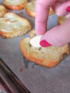 Rubbing garlic to crostini.