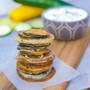 pan fried zucchini chips in a stack with tzatzik sauce