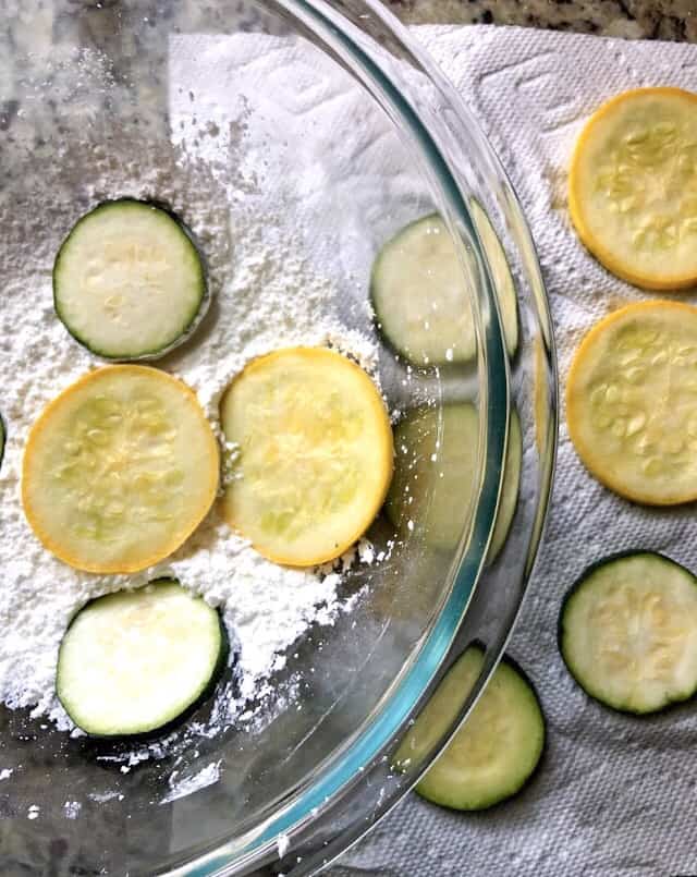 zucchini chips dredged in cornstarch in a bowl.