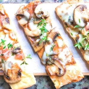 flatbread pizza recipe with mushrooms and onions on cutting board