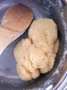 Dough in a pan with wooden spoon.
