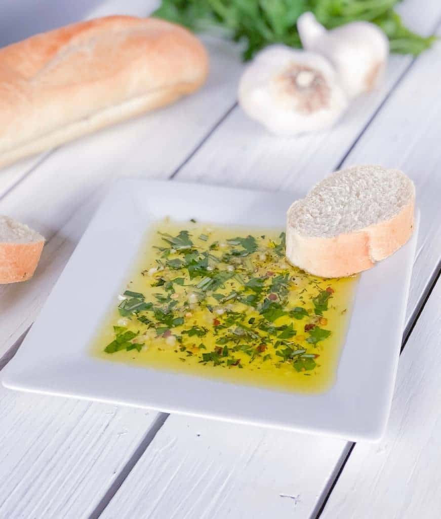 bread dipping oil with fresh herbs on a plate