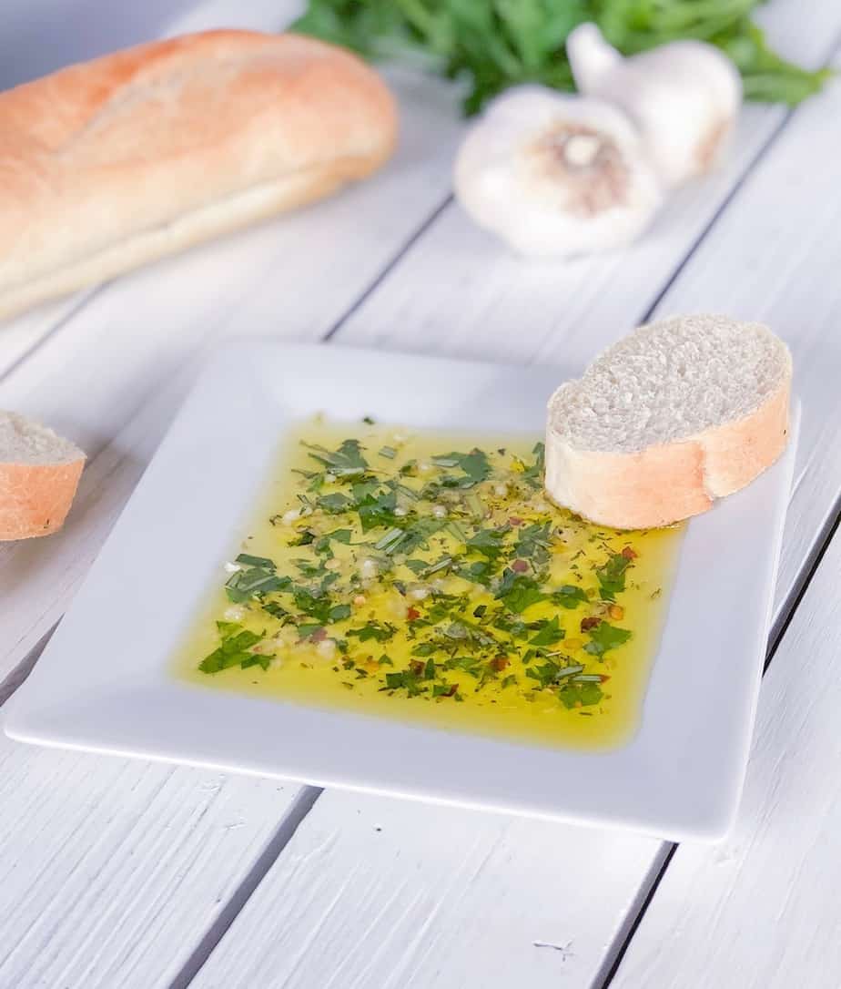 Bread dipping oil on plate with fresh herbs and olive oil.