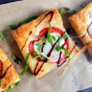 Puff pastry pizza on wooden board with balsamic drizzle.