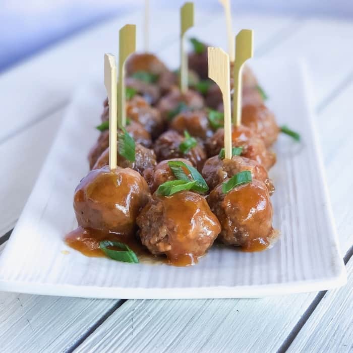 Sweet and sour meatballs skewered on a plate.