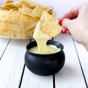 Tortilla chip being dipped into a white cheese sauce without flour.