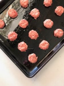 Flattened burger meat on baking dish.