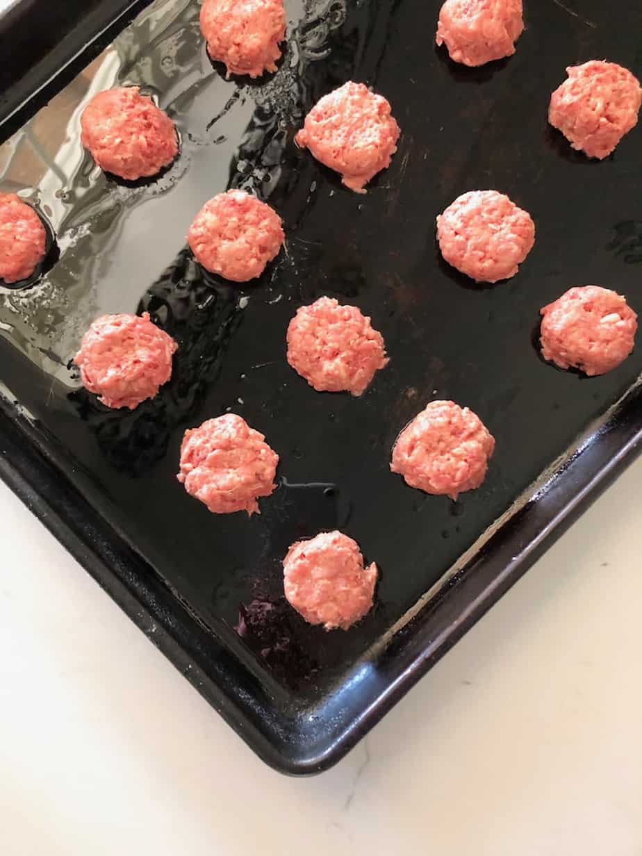 Mini raw patties on a baking sheet.