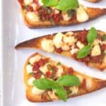 Bruschetta topped with mozzrella and tomatoes.