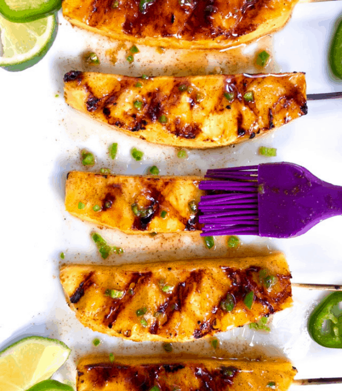 Brushing grilled pineapple with honey lime glaze.