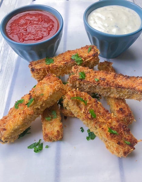 Eggplant fries with dipping sauces on parchment paper.