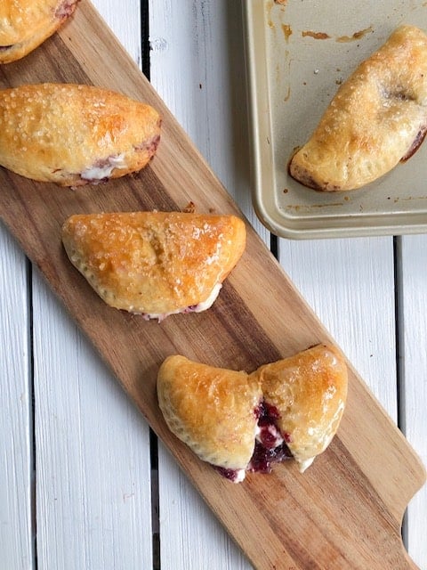 baked sweet empanadas on long cutting board.