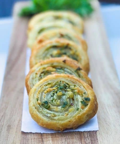 Puff pastry herb pinwheels appetizer on a wooden plank