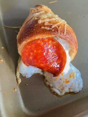 homemade pizza cones appetizer on a baking sheet with cheese oozing out