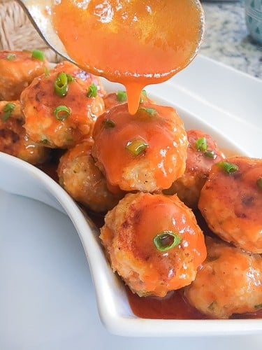 Buffalo sauce turkey meatballs in a bowl with sauce over top.
