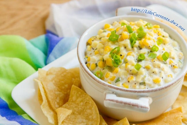 How corn dip inside a mini crock pot with chips on the side.