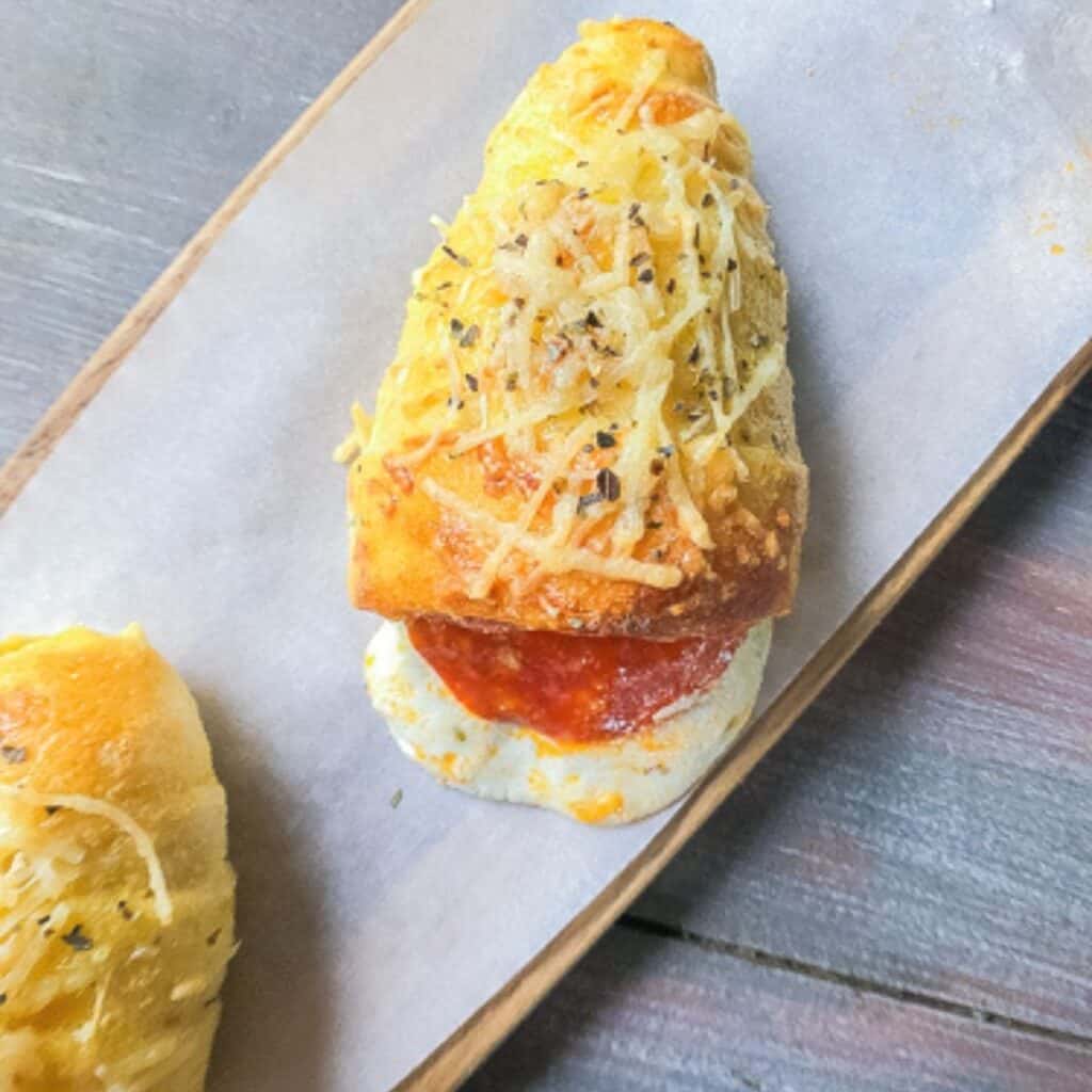 Pizza cone on a board with cheese oozing out.