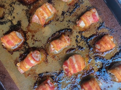 Baked pork wrapped bacon on a baking sheet.