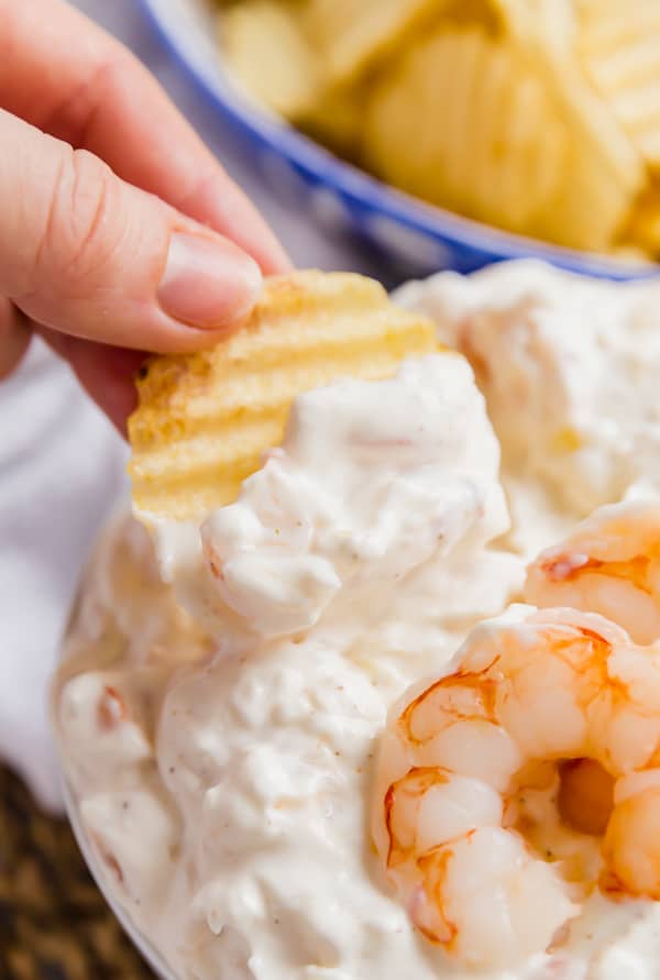 Potato chip dipping into a shrimp dip.