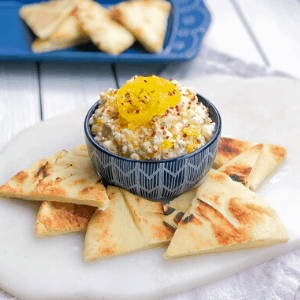 feta cheese dip in a blue bowl with pita bread around it