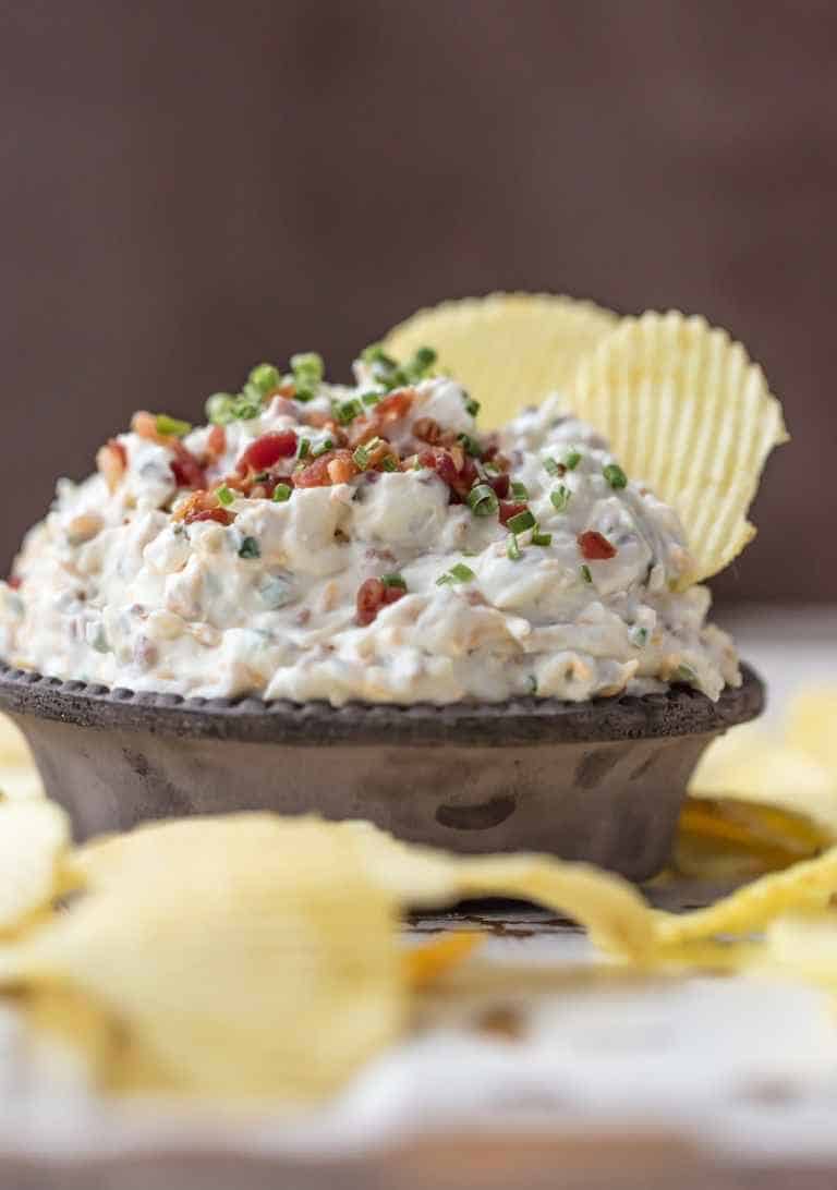 Sour cream onion dip in a bowl with chips in it.