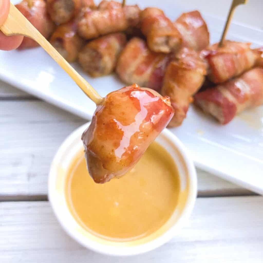 Pork cubes wrapped in bacon served on a skewer.