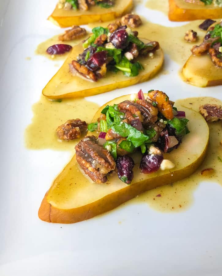 pear slices on a plate topped with pecans cheese and dressing