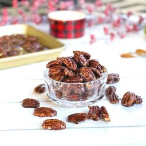 Candied pecans in a clear bowl on a table.