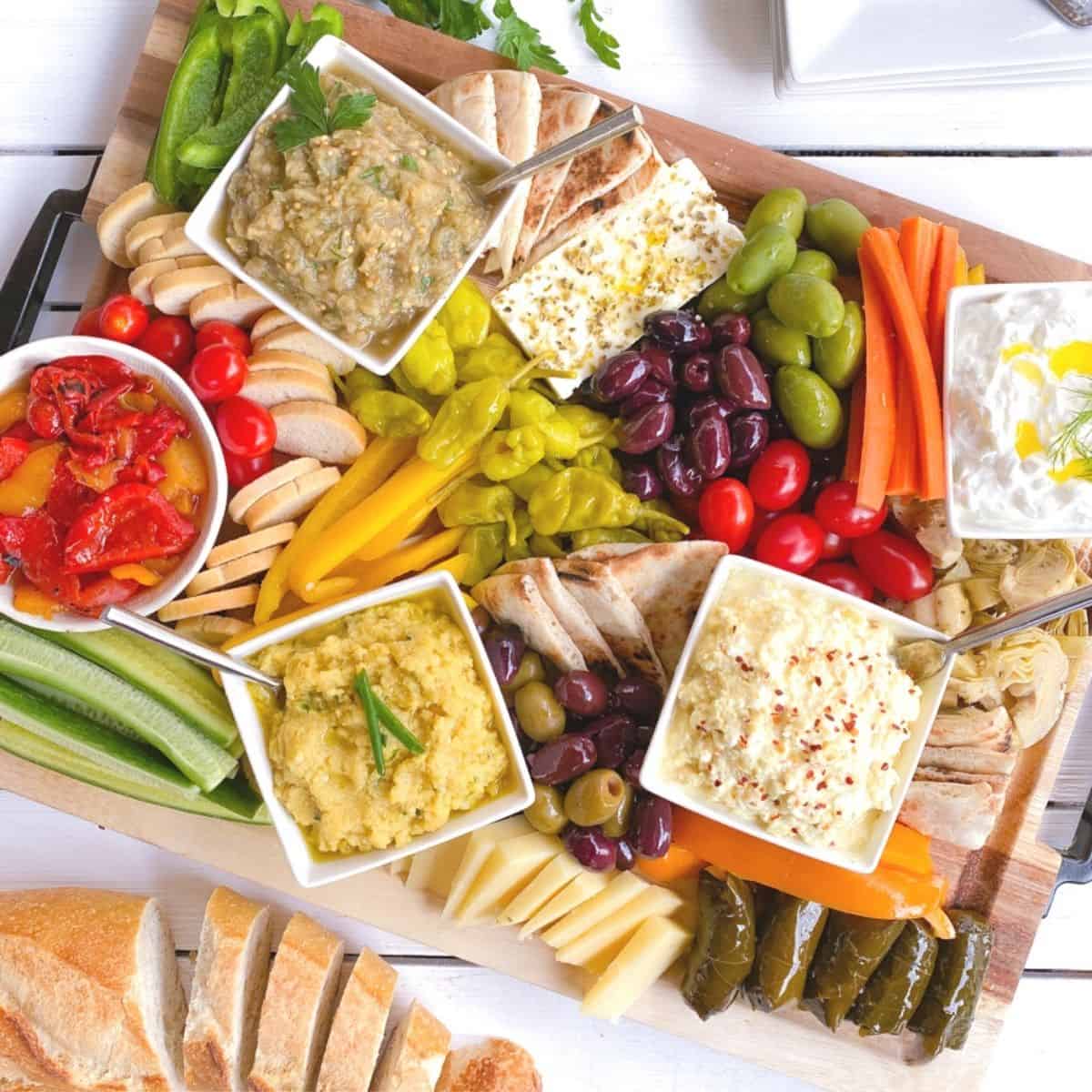 Greek meze spread on a large wooden cutting board.