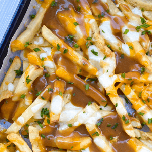 gravy, melted cheddar and mozzarella cheese over french fries on a baking sheet