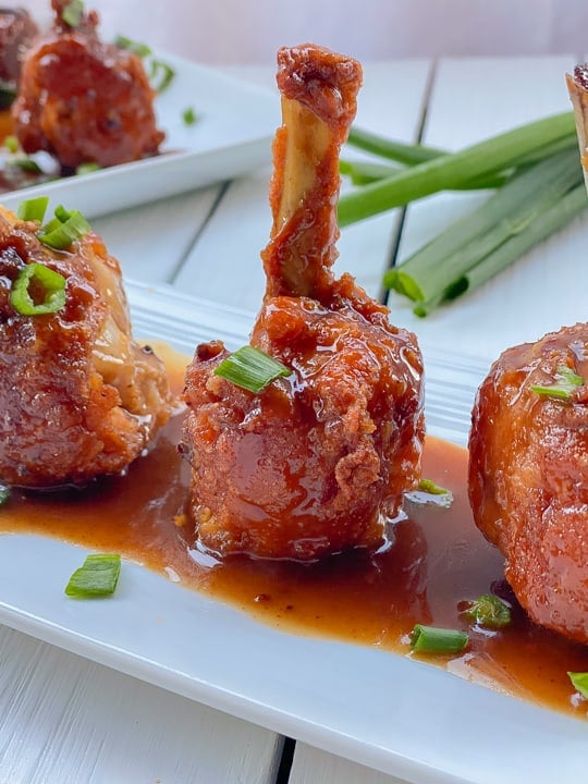 Chicken lollipops on a plate with sesame ginger glaze.