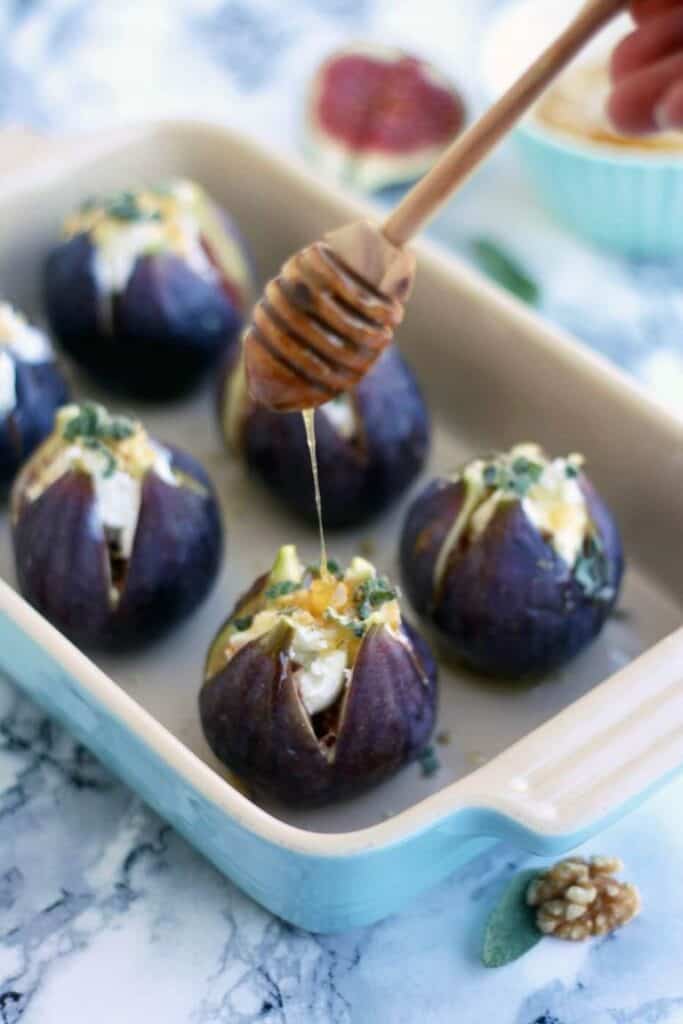 baked figs appetizer stuffed with goat cheese in a dish drizzled with honey