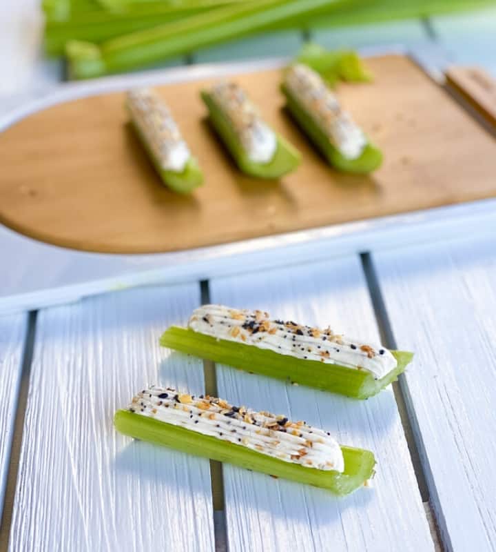 Two celery sticks stuffed with cream cheese topped with everything bagel seasoning.