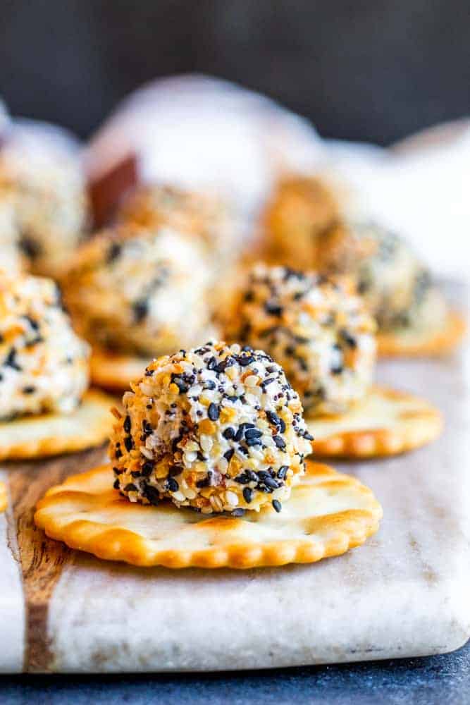 cheese balls snack covered in seasoning over a cracker on a wooden board