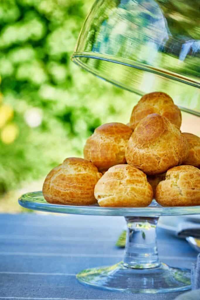 savory profiteroles appetizer stacked on a clear plate with a lid