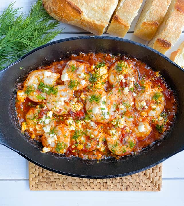 shrimp, feta cheese, tomato sauce in an oval cast iron skillet