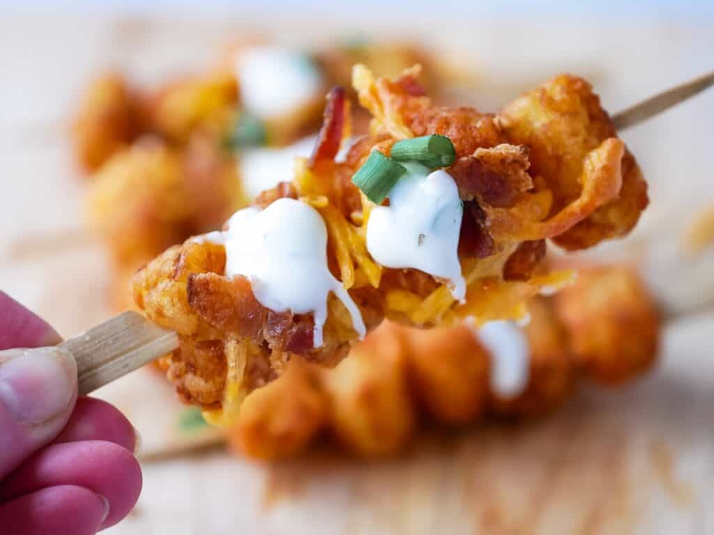 tater tot skewers appetizer with sour cream drizzled on top